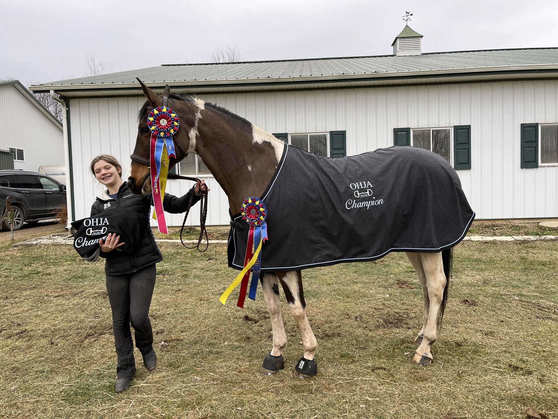 Rylee beaming beside SiSi in her OHJA Champion cooler and rosettes.