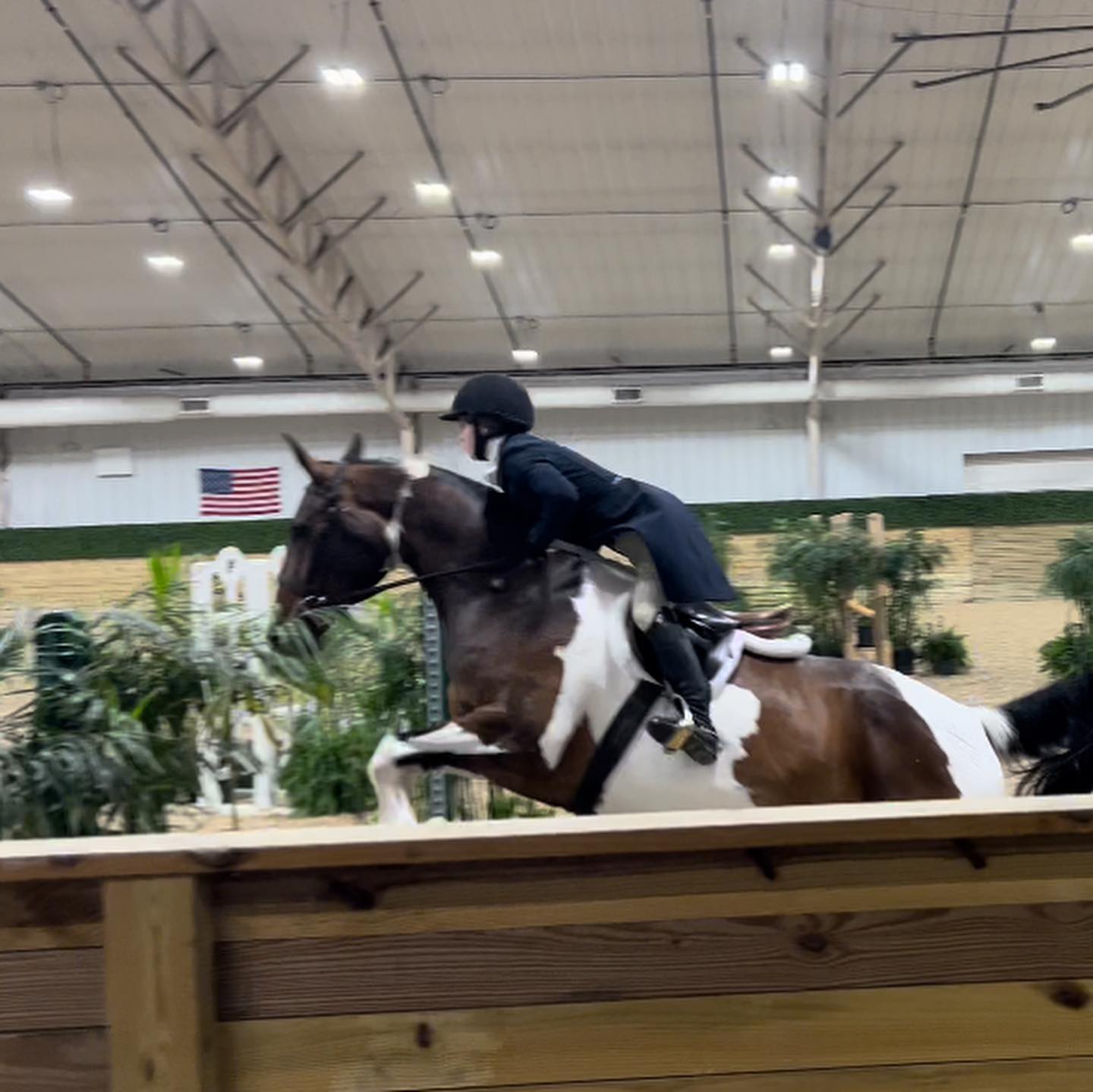 Rylee and SiSi over a fence in an indoor jump round.
