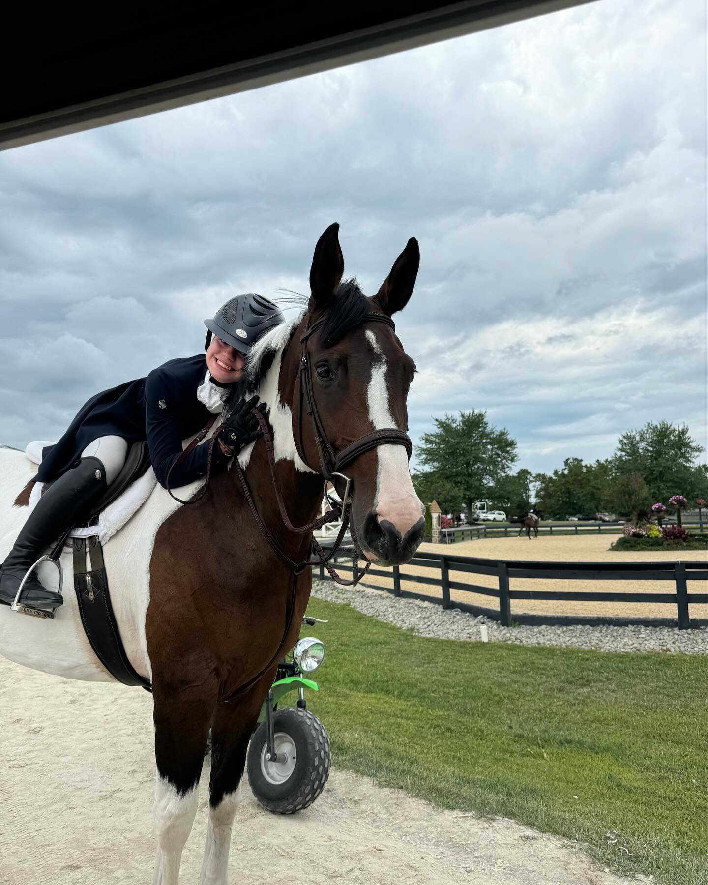 Rylee in her helmet hugging SiSi's neck at the show grounds, a charming candid.