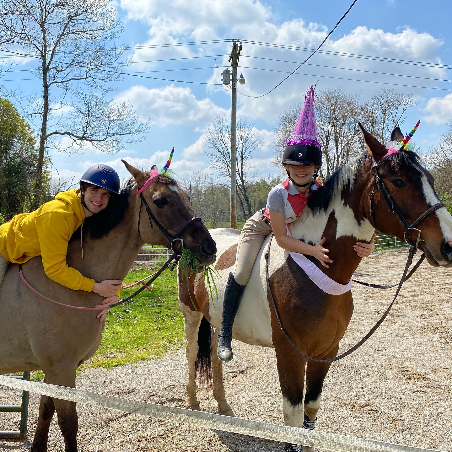 Birthday photo: Rylee mounted on SiSi in a party hat while Kaleb drapes over a dun wearing a unicorn horn.