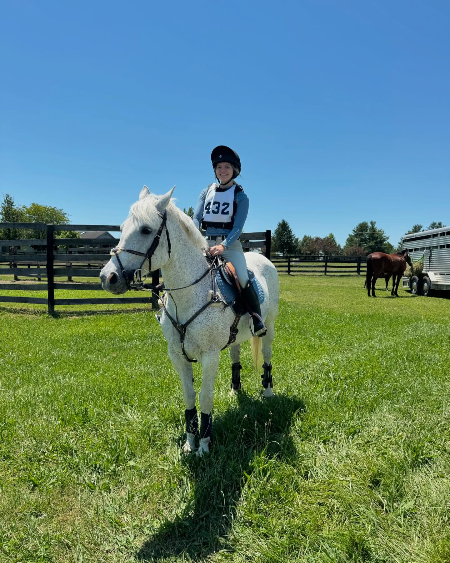 Rylee and Snowflake in cross-country kit wearing bib 432 on a bright day.