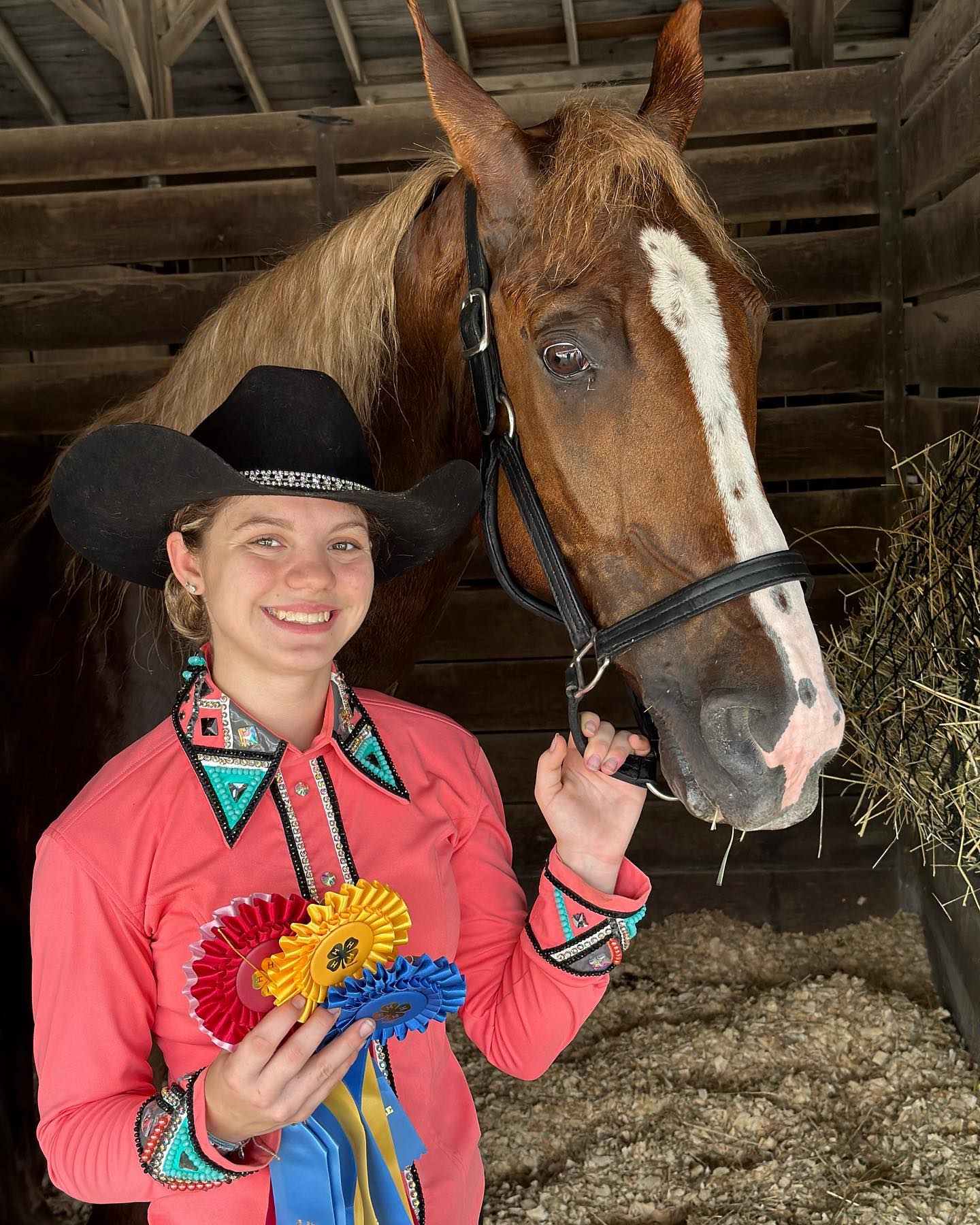 Rylee in a coral western outfit with 4-H rosettes beside Sonny.