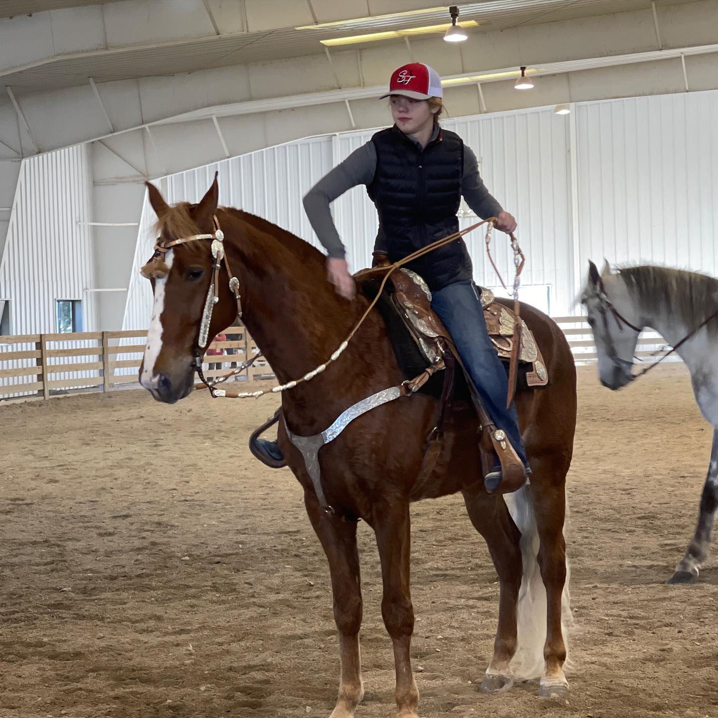 Rylee schooling Sonny under western tack in the indoor arena.