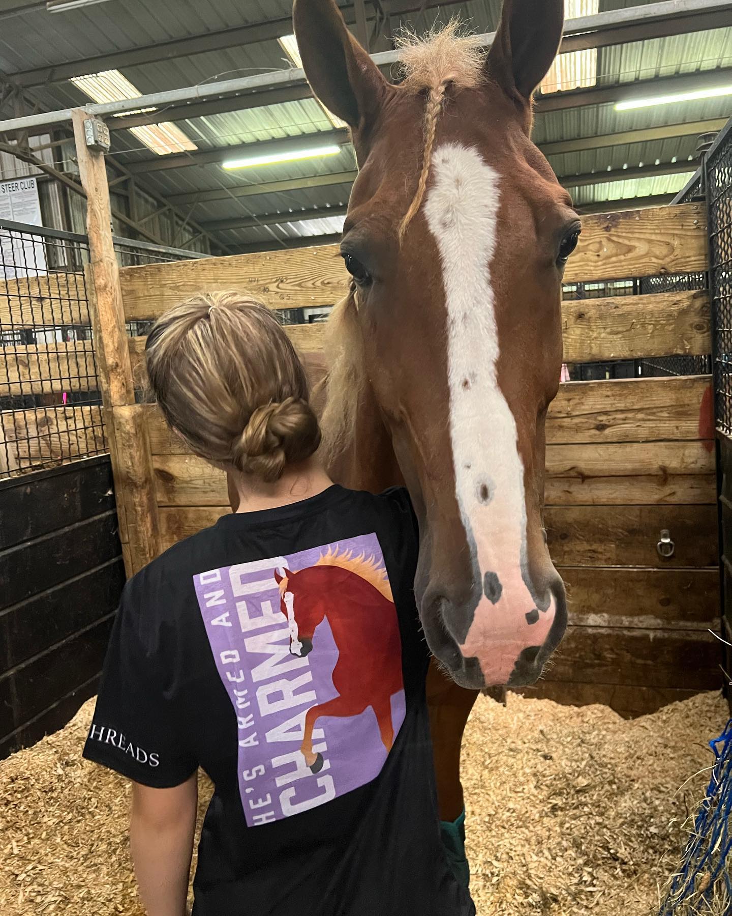 Rylee wearing a He's Armed And Charmed shirt with Sonny in his show stall.