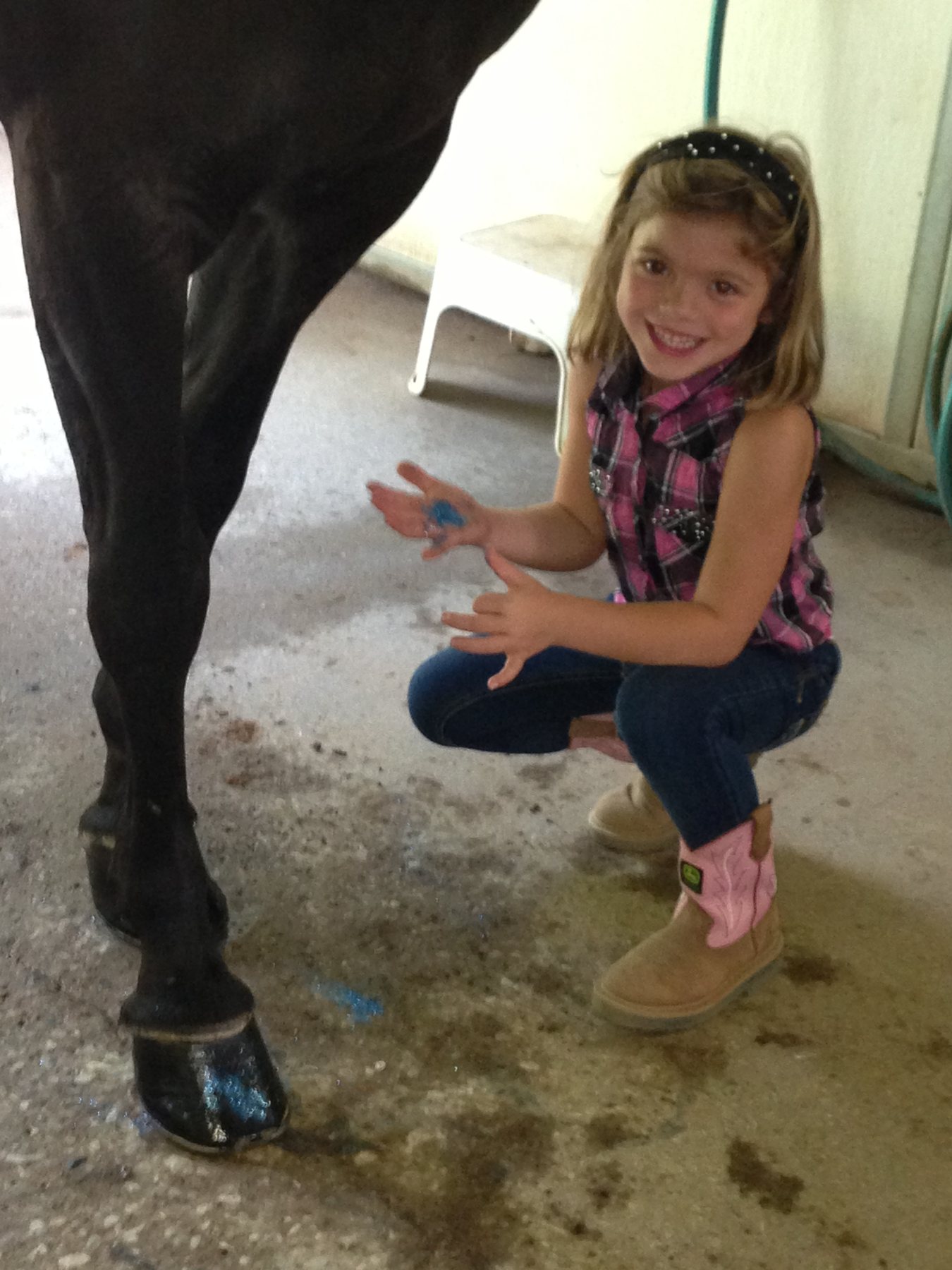 Rylee grinning with hoof-paint on her hands after barn chores.