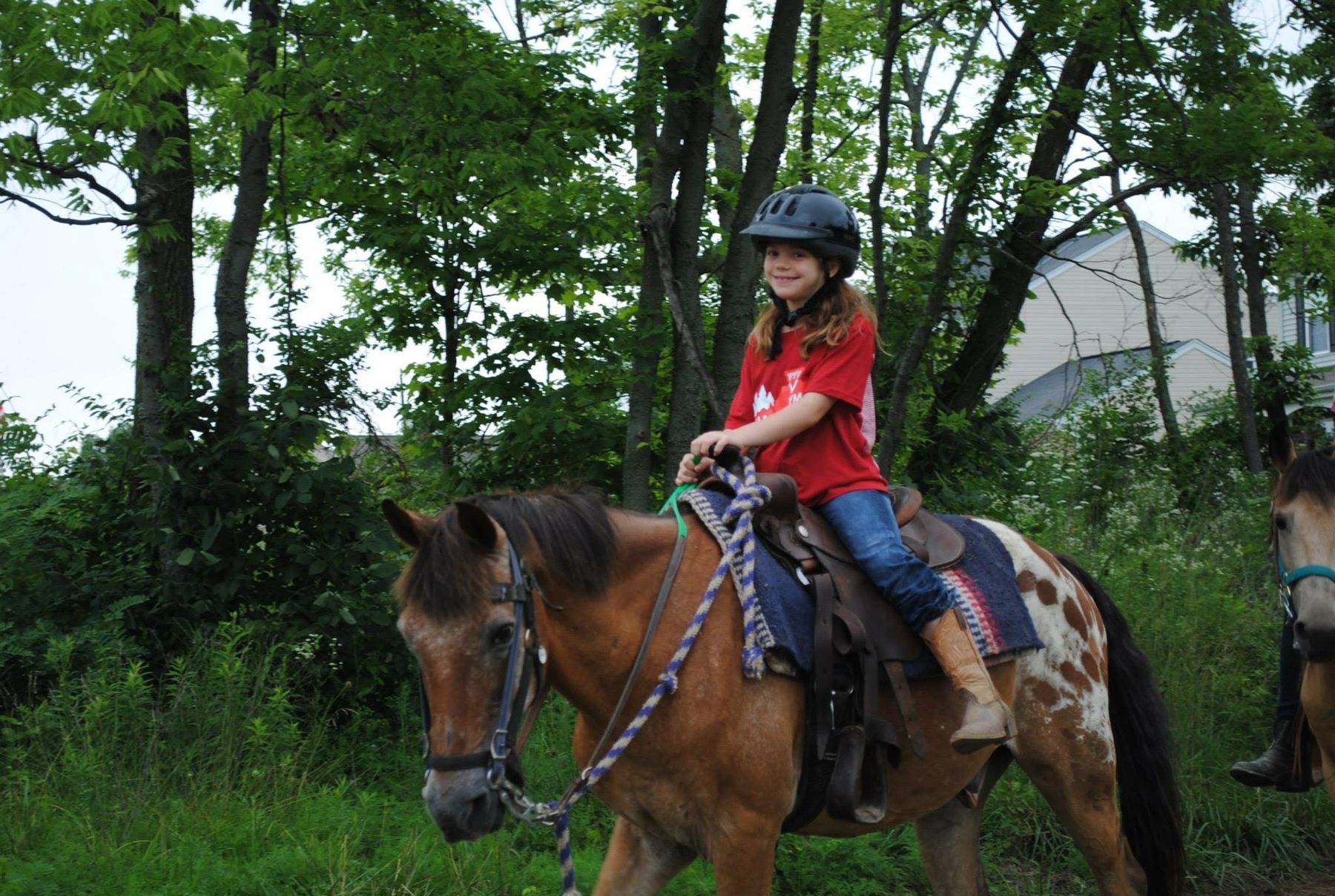 Rylee with a big smile on an appaloosa pony during a green summer trail ride.