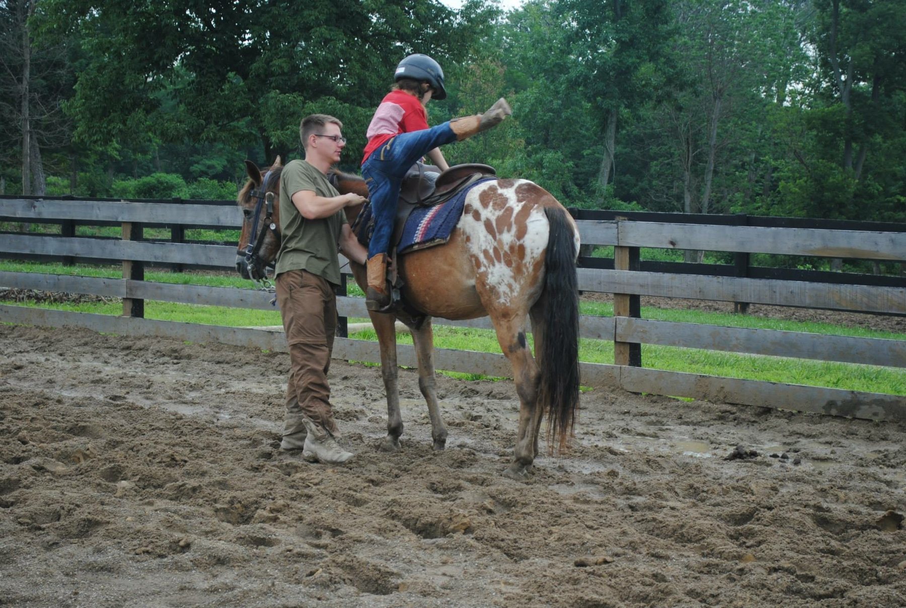 A helper steadies Rylee's dismount from the appaloosa pony.
