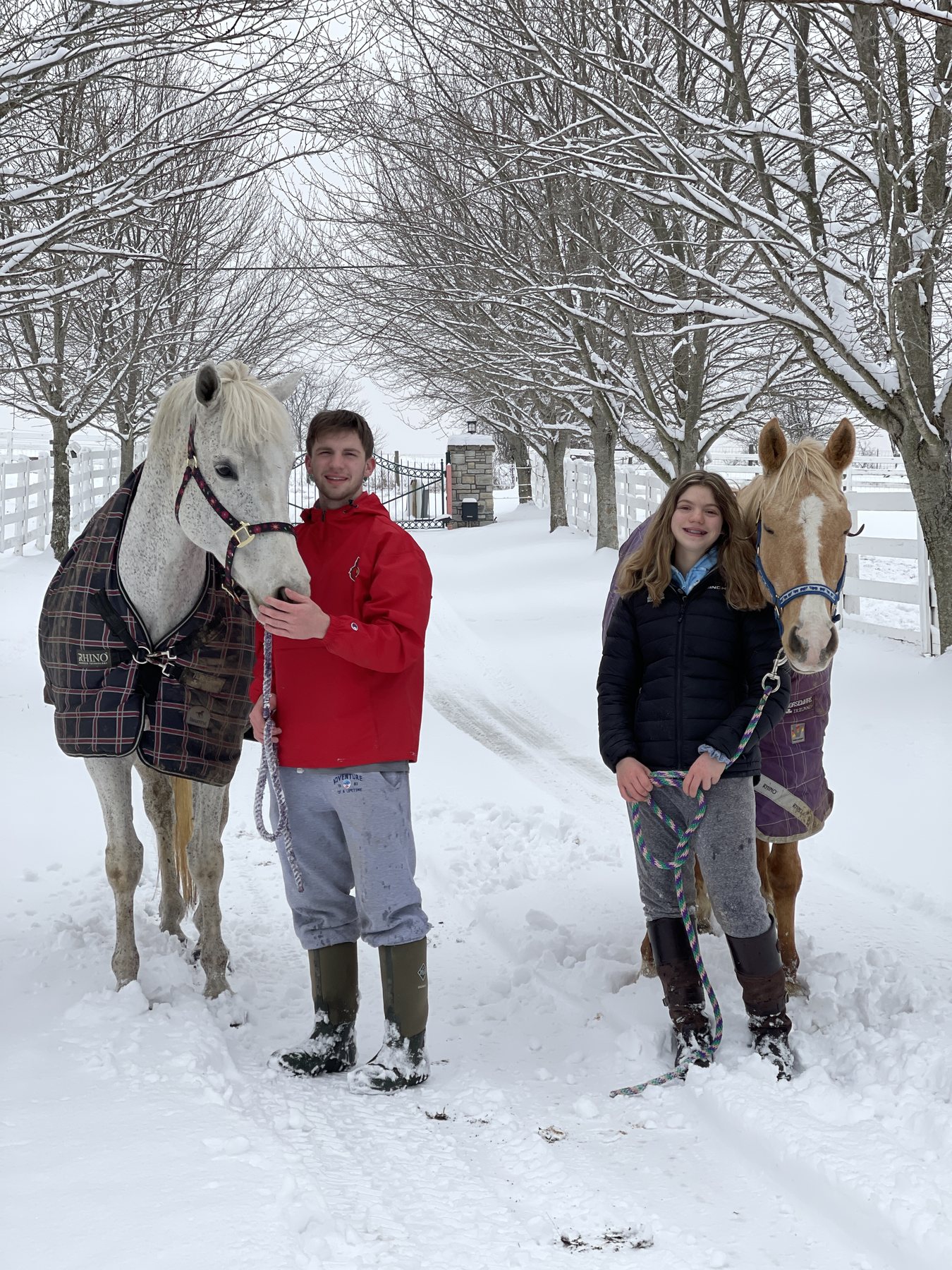 Kaleb and Rylee together with the gray and the palomino among snowy trees.
