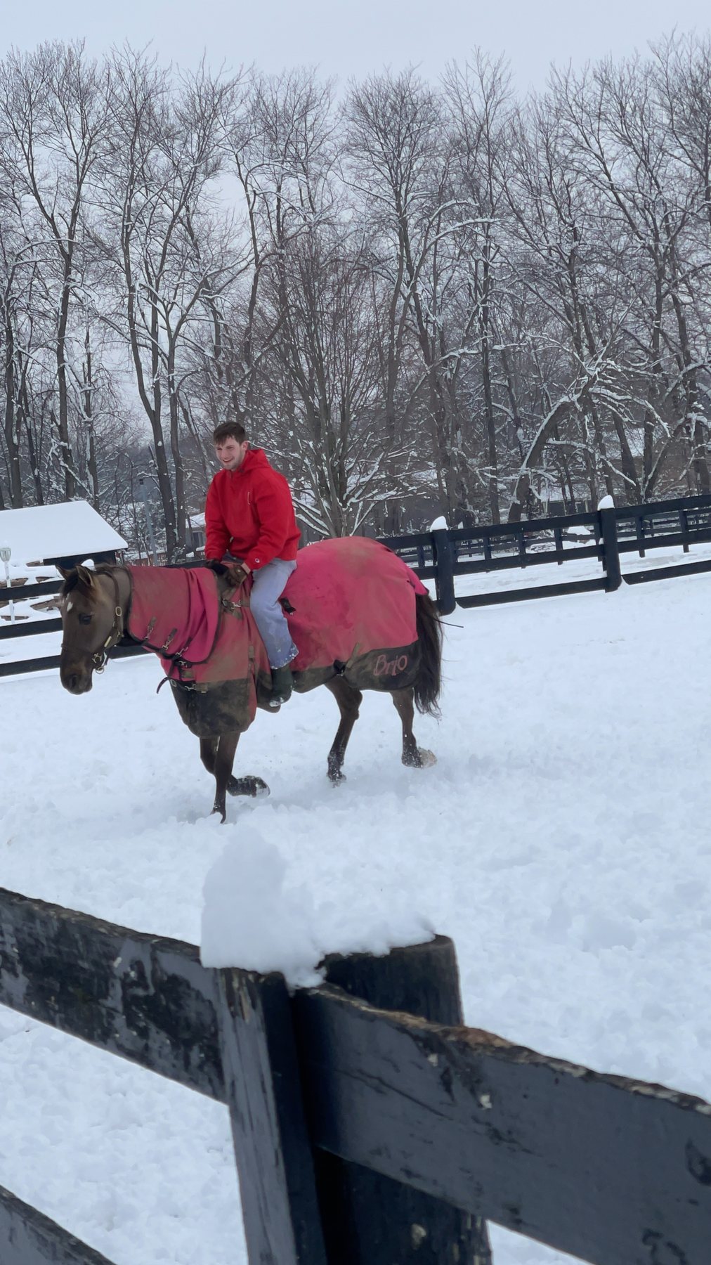 Kaleb and Rylee riding their blanketed horses side by side through the snow.