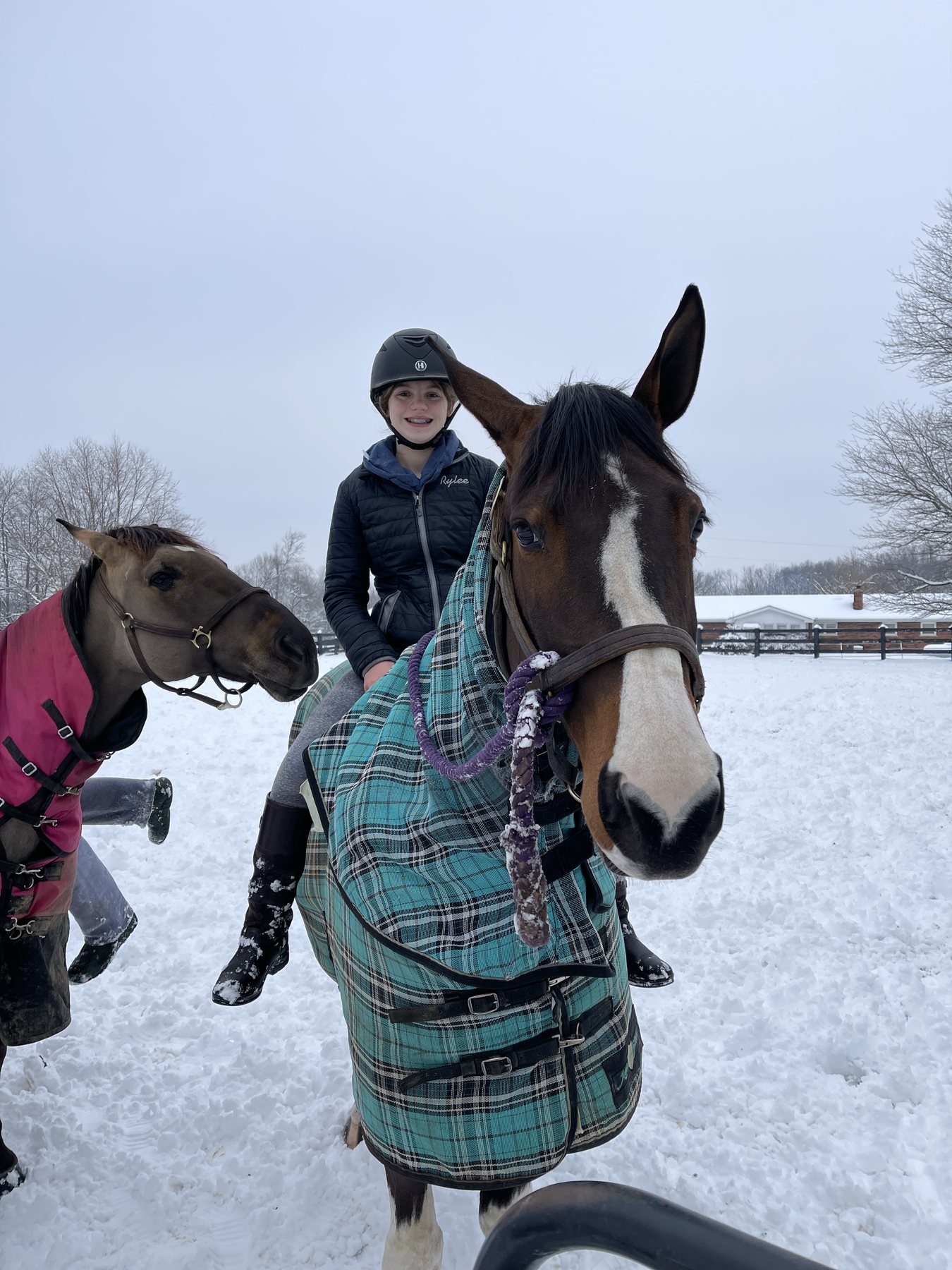 Rylee mounted bareback on the teal-blanketed pinto, grinning through the snowfall.