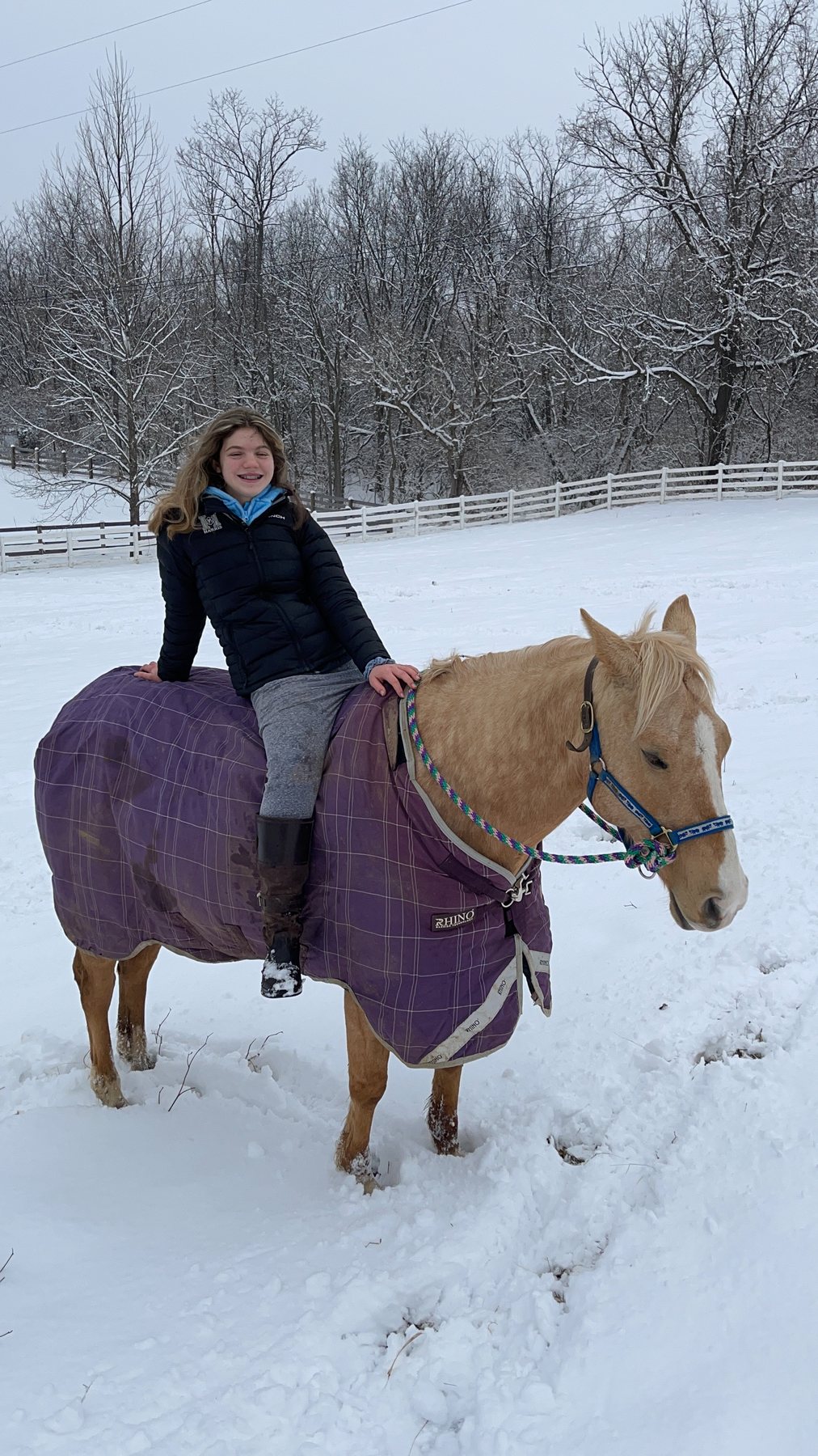 Rylee riding the purple-blanketed palomino bareback through the snow.
