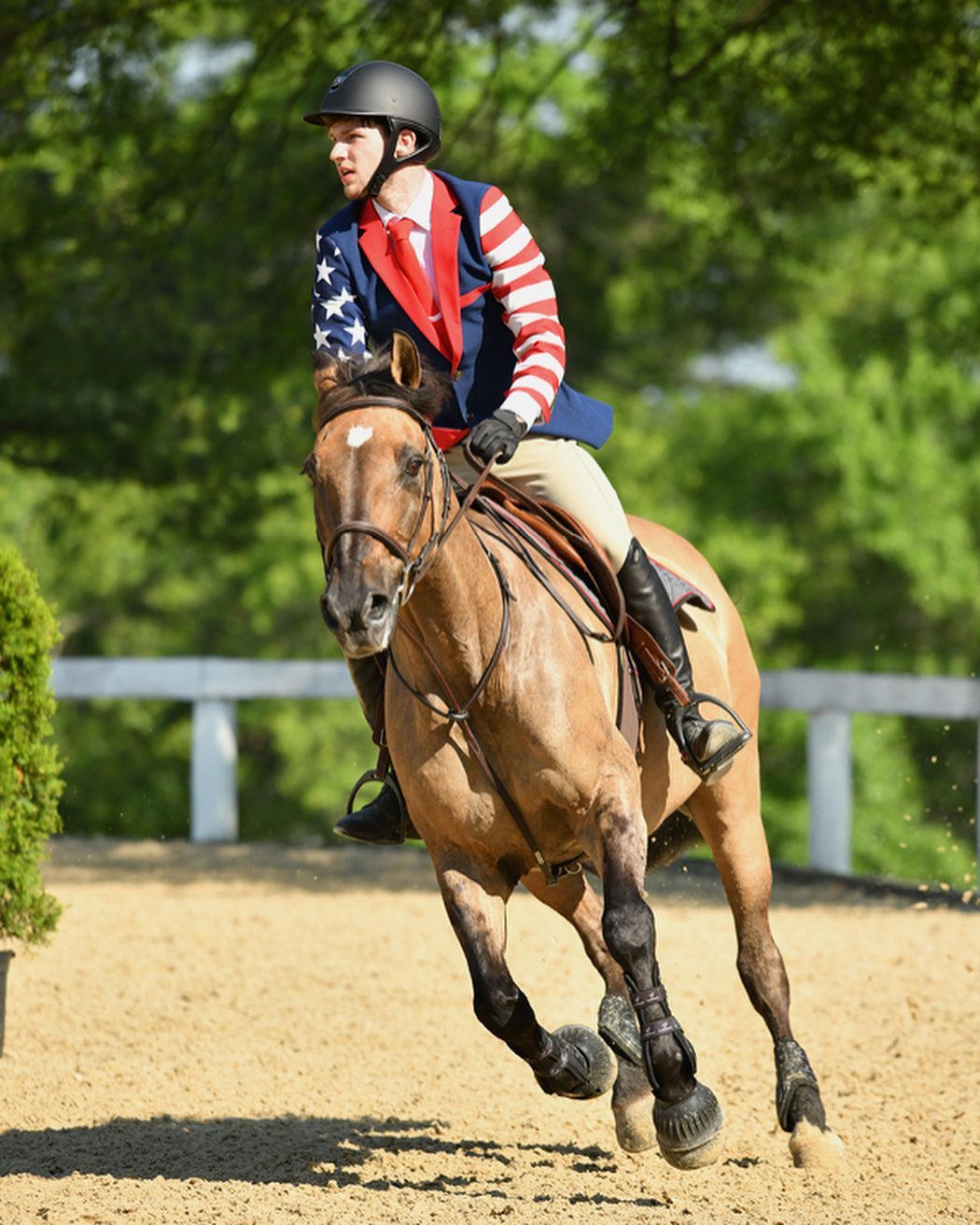 Kaleb in an American-flag coat galloping a buckskin under saddle in a striking action shot.