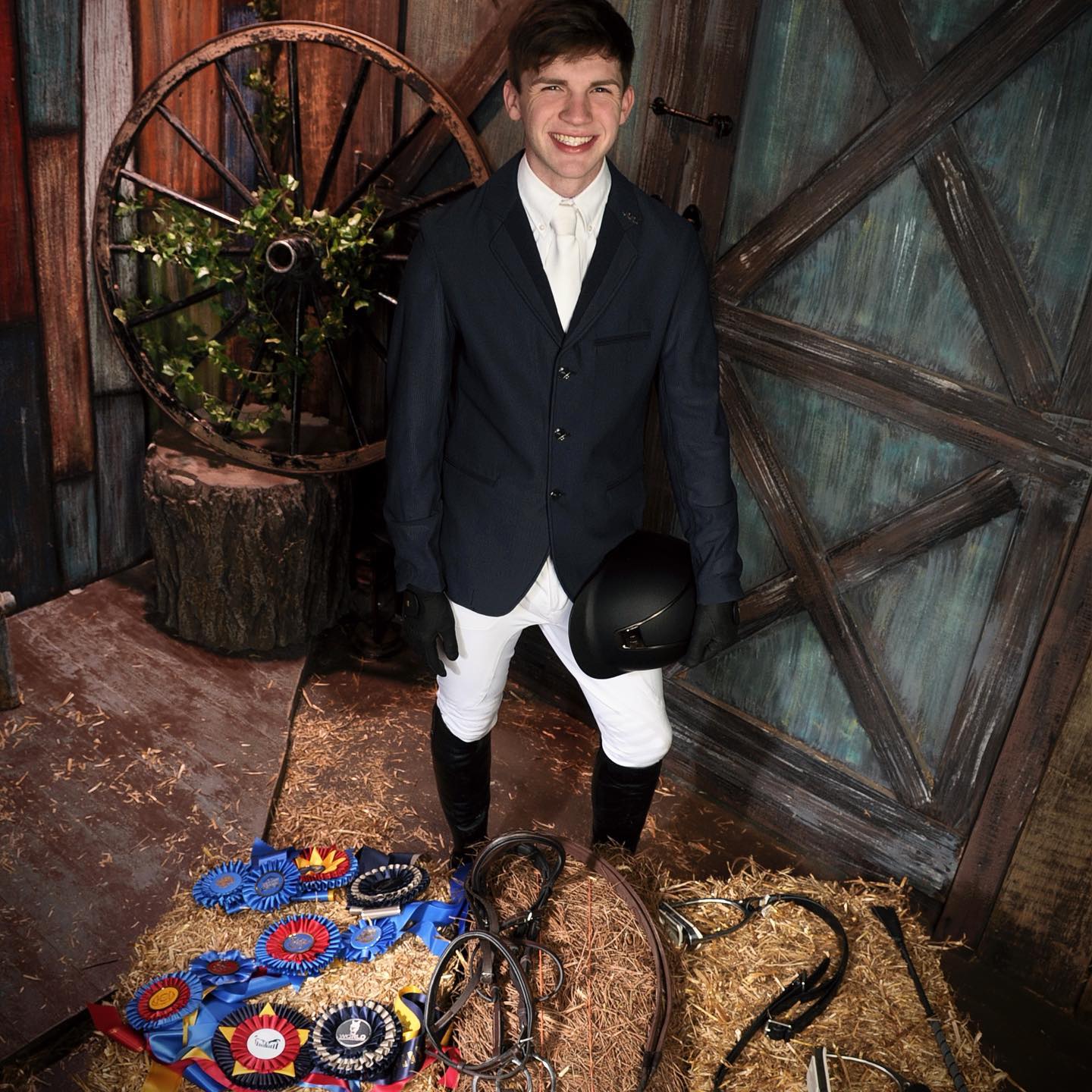 A professional studio portrait of Kaleb with ribbons and tack.