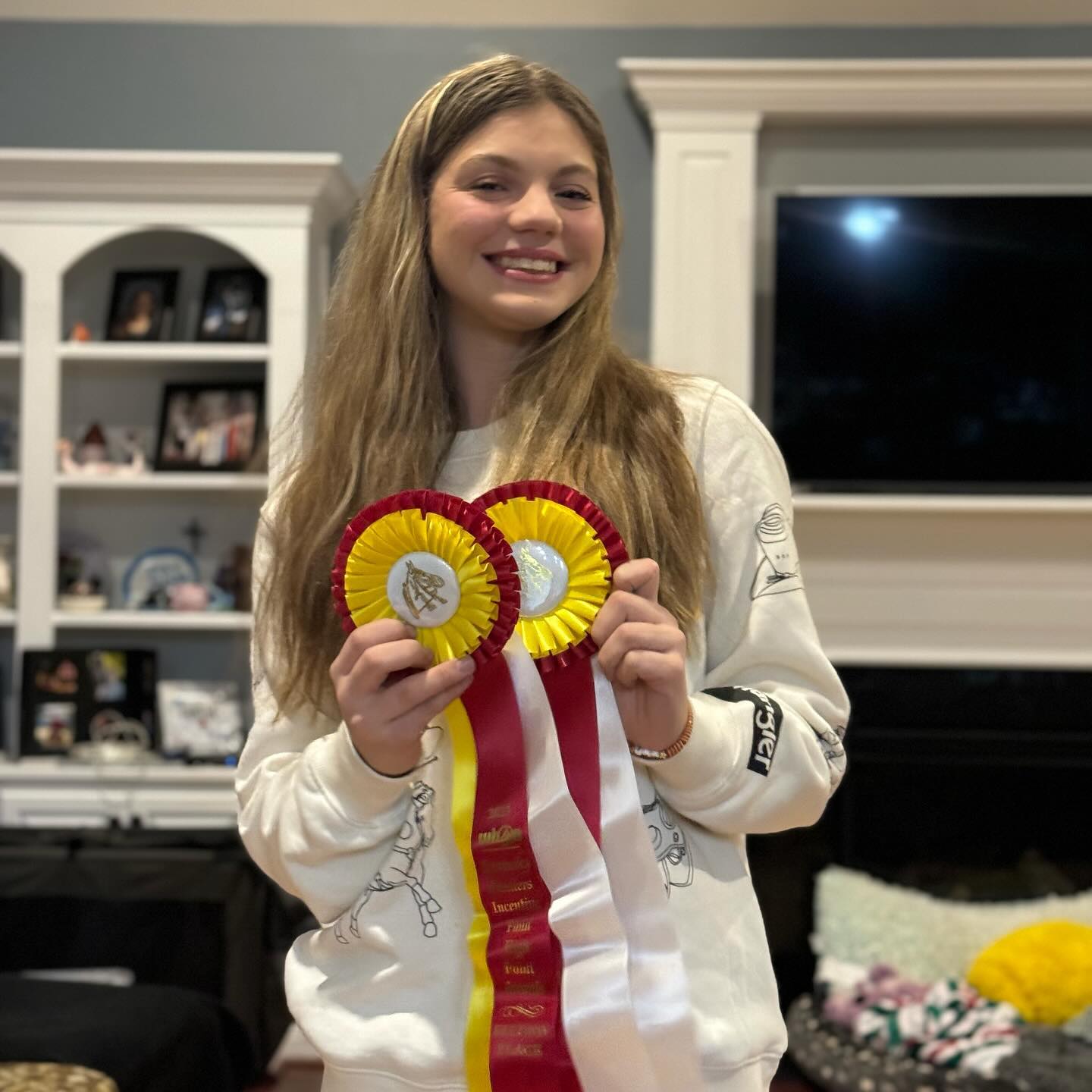 Rylee at home holding two Breeders Incentive Fund rosettes.