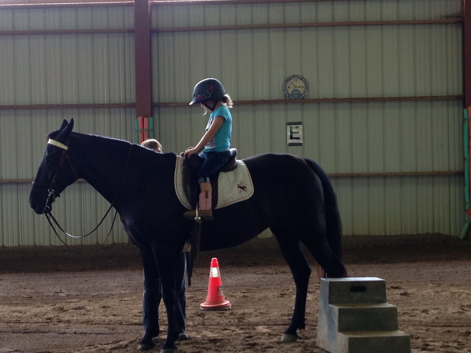 A young Rylee sitting tall on Bella, a black mare, during an early riding lesson.