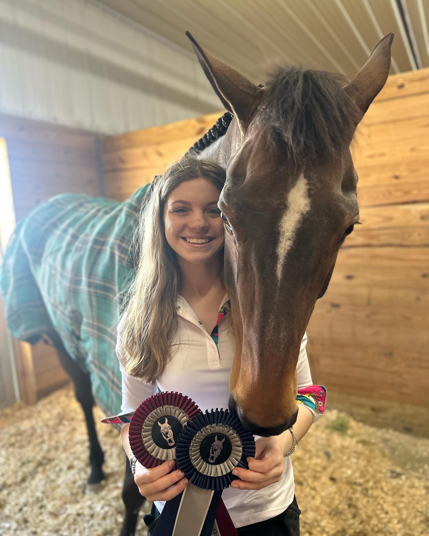 Rylee hugging a braided bay while holding two halter-class rosettes.