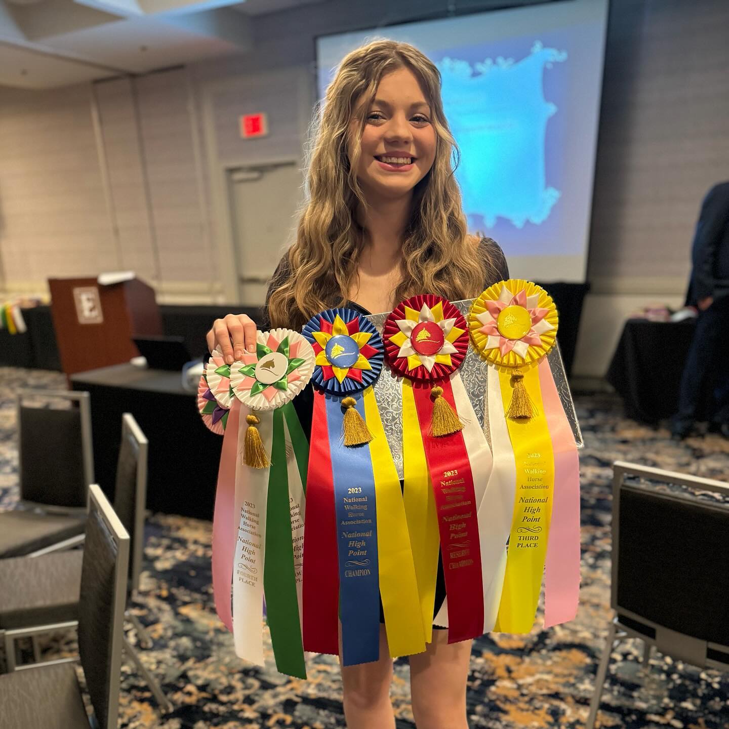 Rylee at the NWHA awards banquet holding 2023 National High Point rosettes.