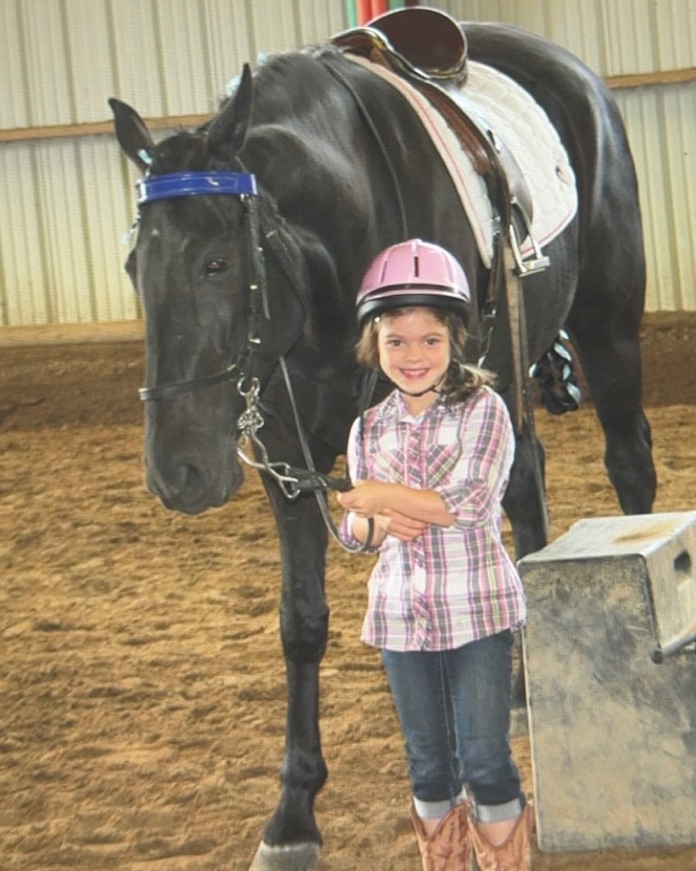 Throwback photo of a young Rylee in a pink helmet with a black horse tacked English.